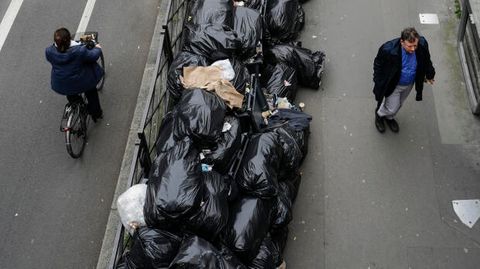 Straßenszene in Paris mit Fahrradfahrer und Fußgänger zwischen Müllbergen