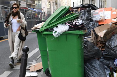In Paris spaziert eine Frau an einem der unzähligen Müllberge vorbei