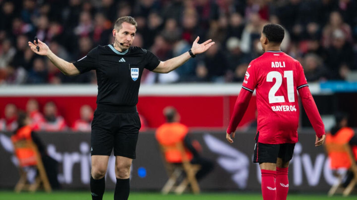 Schiedsrichter Tobias Stieler gestikuliert neben Leverkusens Amine Adli
