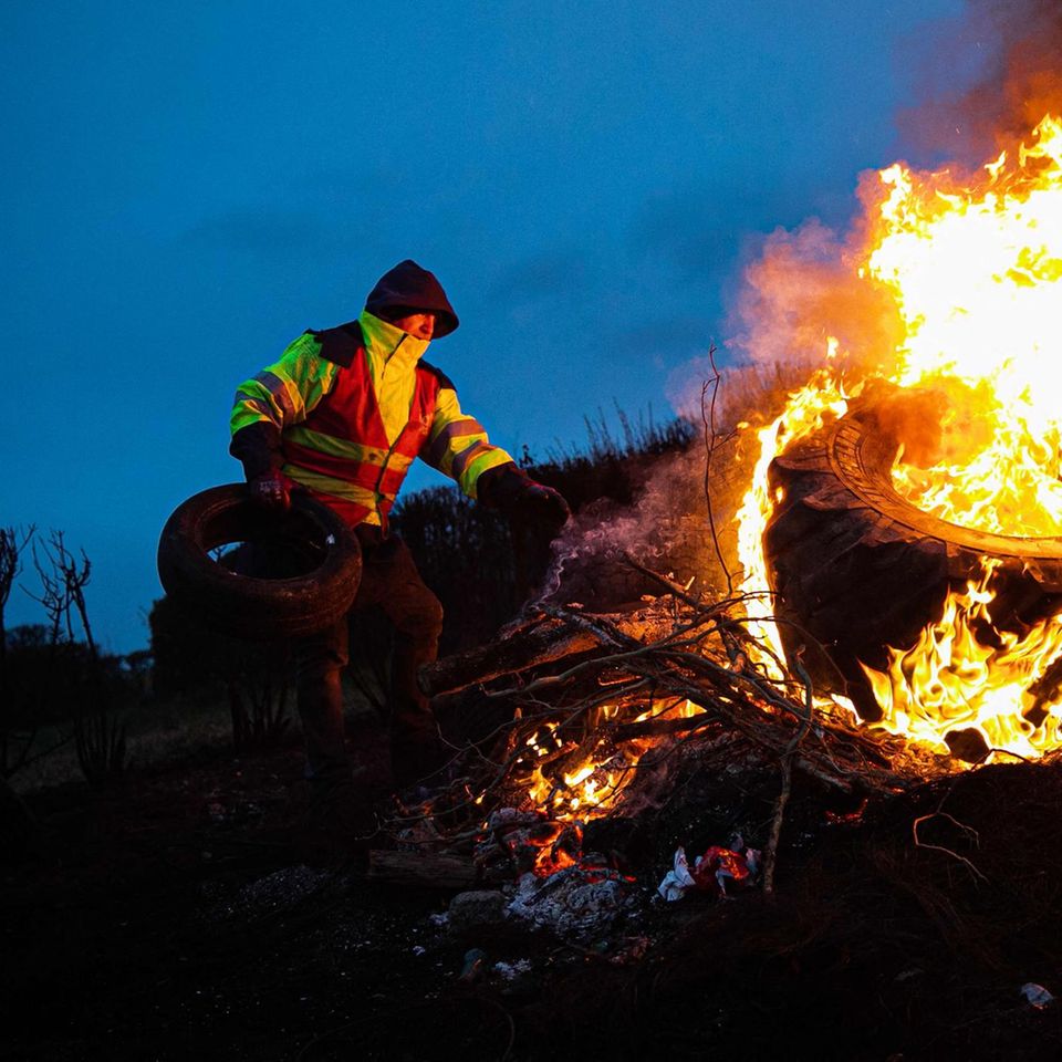 Ein Mitglied der Gewerkschaft Confederation Generale du travail (CGT) wirft Reifen auf ein Lagerfeuer
