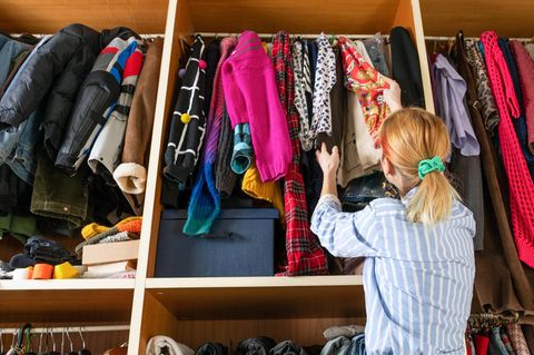 Eine Frau geht durch Oberteile in ihrem Kleiderschrank