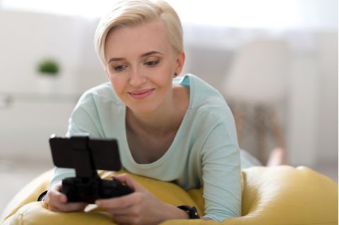 Eine Frau spielt am Smartphone mit ihrem Handy-Controller