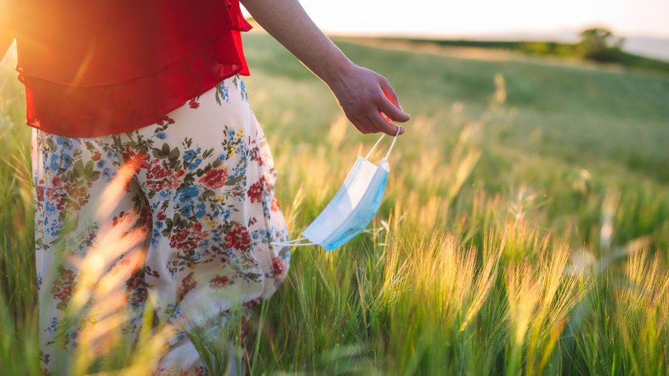 Allergiesaison: Frau läuft mit Maske über ein Feld