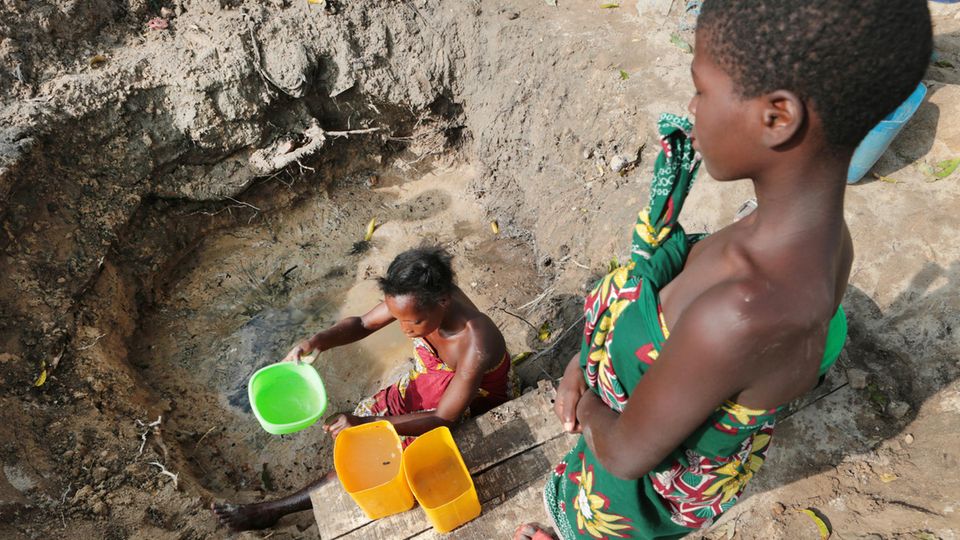 Eine Frau holt Wasser aus einer ungeschützten Quelle in Mosambik