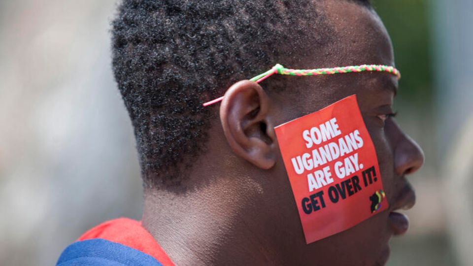 Ein ugandischer Mann trägt einen Aufkleber mit der Aufschrift "Einige Ugander sind schwul. Finde dich damit ab"