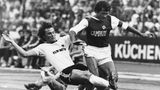 Der Hamburger SV, hier mit Georg "Schorsch Volkert im Einsatz, gehörte ebenfalls zu den Vereinen, die schnell reagierten und ab der Saison 1974/75 die freie Fläche gewinnbringend veräußerten. Für 500.000 DM im Jahr stellten sie ihre Brust für den italienischen Likör Campari zur Verfügung. Der Profi, der hier zu einem Tackling (damals: Grätsche) gegen Volkert ansetzt, ist Bundesliga-Rekordspieler Charlie Körbel von Eintracht Frankfurt. Die SGE gewann als Sponsor den Rasierapparate-Hersteller Remington und gehörte ebenfalls zu den ersten. Vereinen, die die neue Einnahmequelle nutzen.