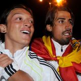 Mesut Özil und Sami Khedira kicken zusammen bei Real. 2011 feiern sie den Gewinn der Copa del Rey, des spanischen Pokals. Insgesamt spielt Özil drei Jahre für die Königlichen und gewinnt neben dem Pokal Meistertitel und Supercup. Auch wenn der feine Techniker torgefährlich ist, seine große Kunst besteht darin, Tore genial vorzubereiten. 2013 wechselt er für 50 Millionen Euro von Real Madrid zu Arsenal London, was damals in Spanien für viel Unverständnis sorgt. Ronaldo schimpft am lautesten, weil er seinen genialen Passgeber verliert. Hintergrund ist, dass Özils Vater die Verhandlungen um eine Vertragsverlängerung durch Türknallen und überzogene Forderungen an die Wand gefahren hat. Kurz danach trennt sich Özil von seinem Vater als Berater.