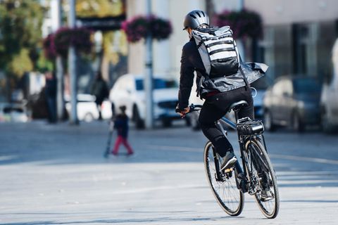 Rolltop-Rucksack: Mann mit Rolltop-Rucksack auf dem Fahrrad