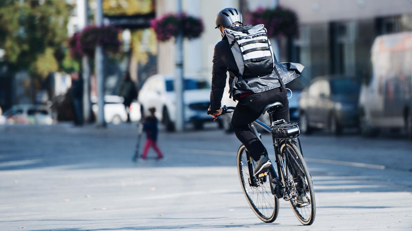 Rolltop-Rucksack: Mann mit Rolltop-Rucksack auf dem Fahrrad