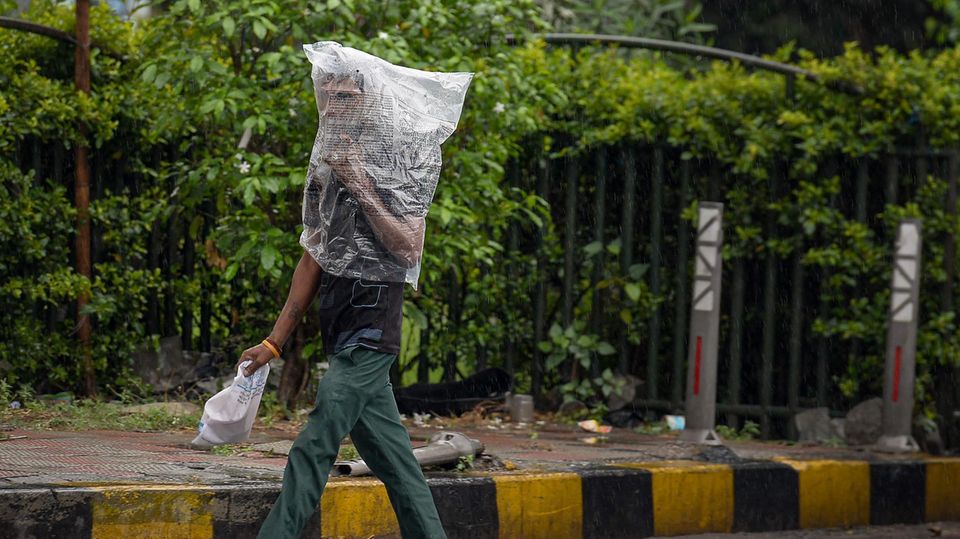 Jalandhar, Indien. Hoffentlich hat der Mann an Luftlöcher gedacht: Ein Fußgänger in der Stadt im Bundesstaat Punjab schützt sich mit einer Plastiktüte vor Regen.