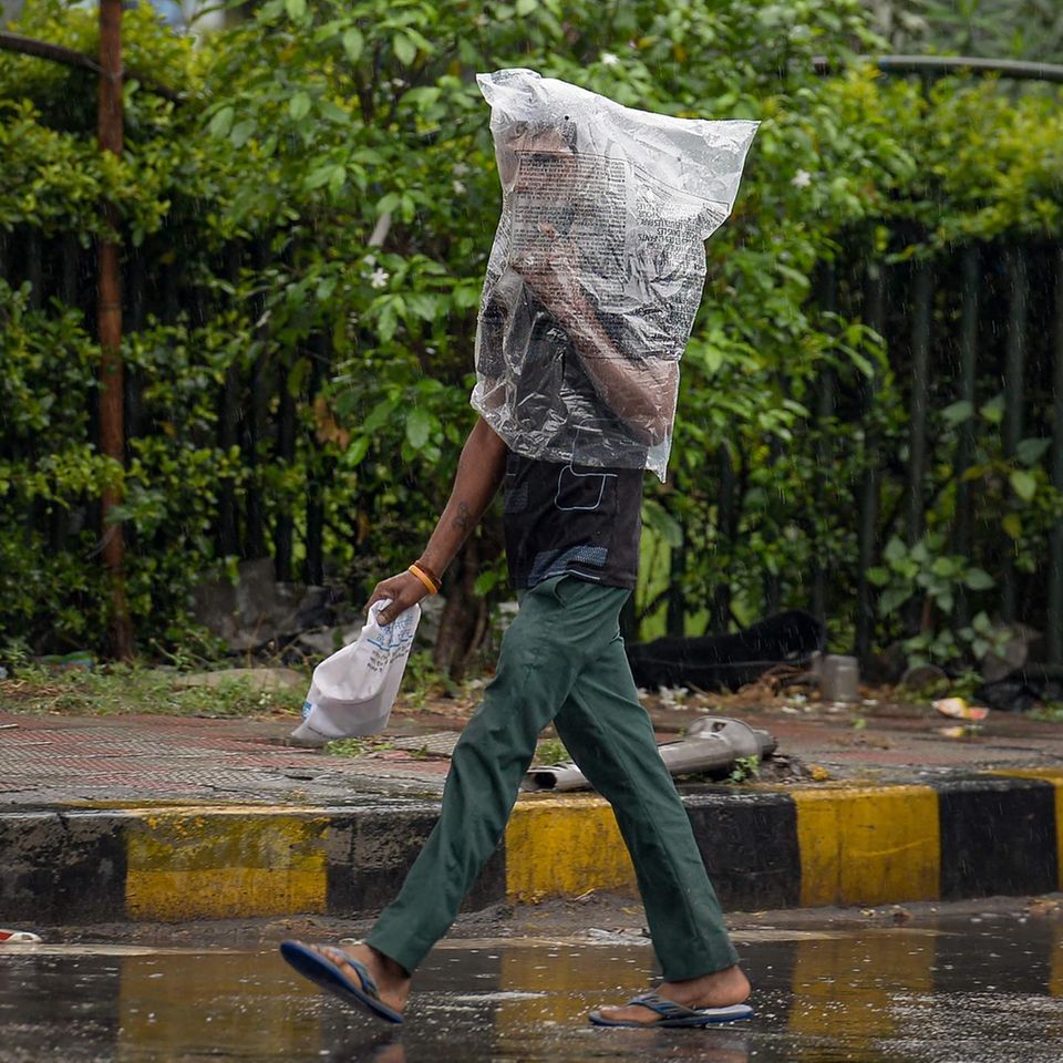 Jalandhar, Indien. Hoffentlich hat der Mann an Luftlöcher gedacht: Ein Fußgänger in der Stadt im Bundesstaat Punjab schützt sich mit einer Plastiktüte vor Regen.