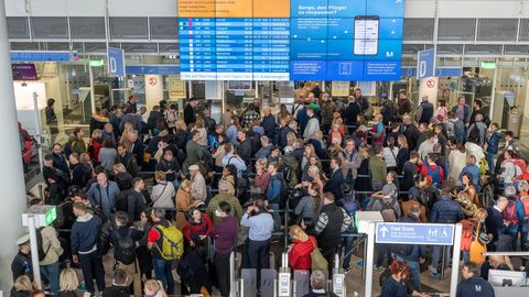 Passagiere stehen in der Abflughalle des Flughafen München in Schlangen an, um zur Sicherheitskontrolle zu gelangen