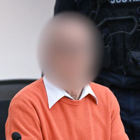 Ein weißer Mann in orangem Pullover sitzt im Oberlandesgericht Stuttgart auf der Anklagebank