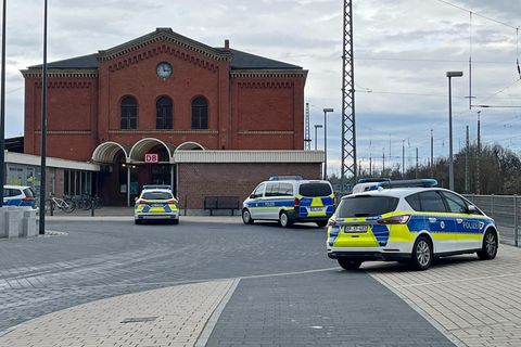 Nach einem Angriff in einem Regionalzug stehen vier Polizeiwagen vor dem Bahnhof in Guben, Brandenburg