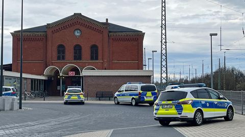 Nach einem Angriff in einem Regionalzug stehen vier Polizeiwagen vor dem Bahnhof in Guben, Brandenburg