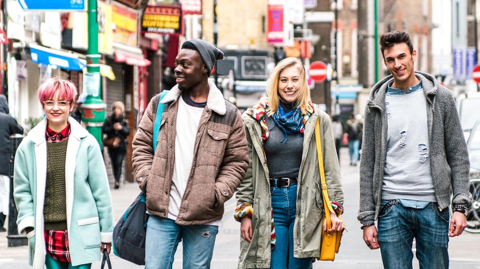 Vier Jugendliche gehen auf einer Straße in Großbritannien: zwei weiße Frauen sowie eine weißer und ein schwarzer Mann