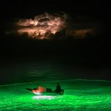 Ein Beiboot leuchtet ins Meer hinein. Außer den Bagan-Plattformen fischen auch Trawler mit Licht