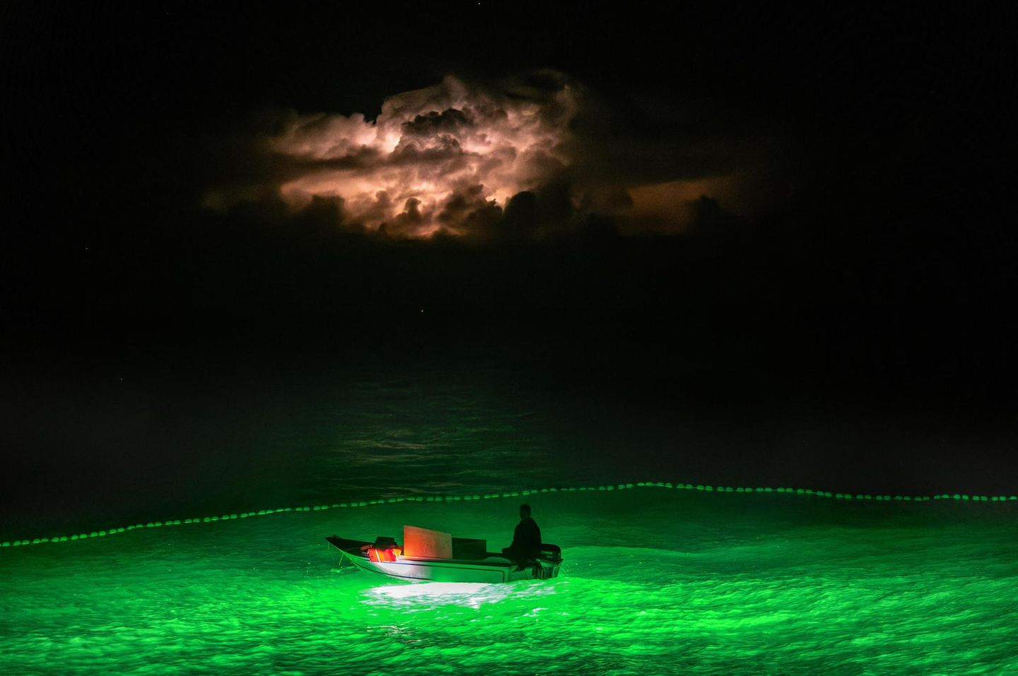 Ein Beiboot leuchtet ins Meer hinein. Außer den Bagan-Plattformen fischen auch Trawler mit Licht