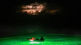 Ein Beiboot leuchtet ins Meer hinein. Außer den Bagan-Plattformen fischen auch Trawler mit Licht