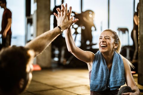 Eine fröhlich lachende Sportlerin klatscht sich mit ihrem Trainingspartner ab