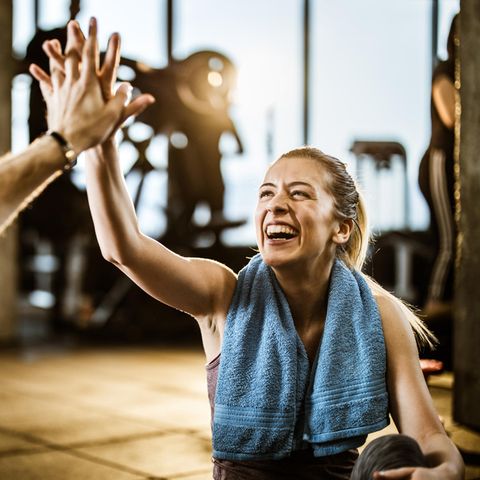 Eine fröhlich lachende Sportlerin klatscht sich mit ihrem Trainingspartner ab