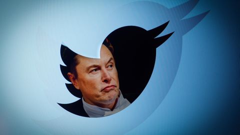 Elon Musk ist durch ein transparentes Twitter-Logo zu sehen