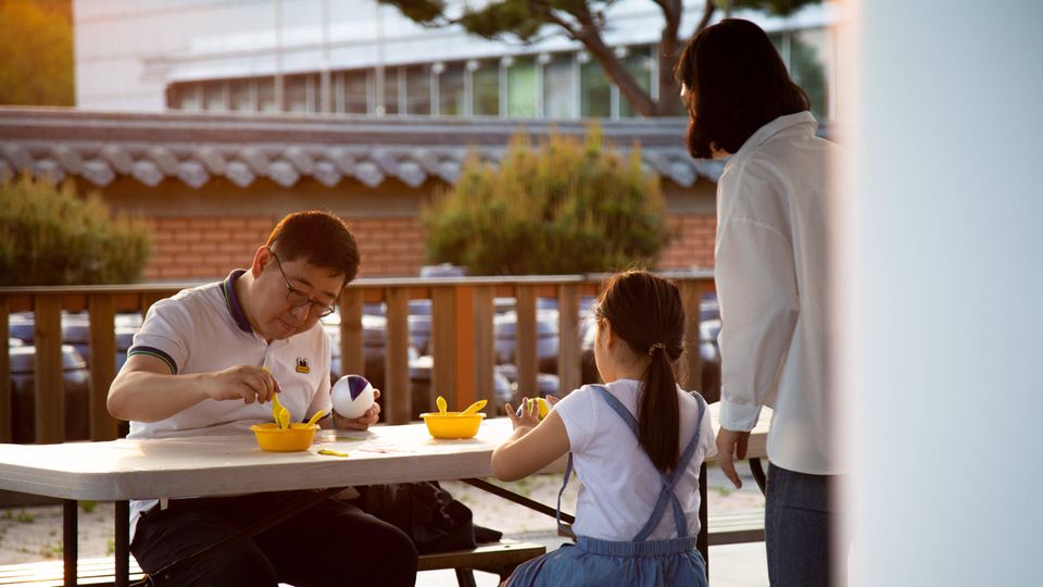 Eine dreiköpfige Familie in Südkorea sitzt am Tisch und isst gemeinsam