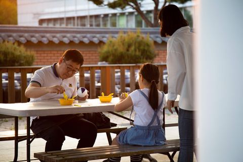 Eine dreiköpfige Familie in Südkorea sitzt am Tisch und isst gemeinsam