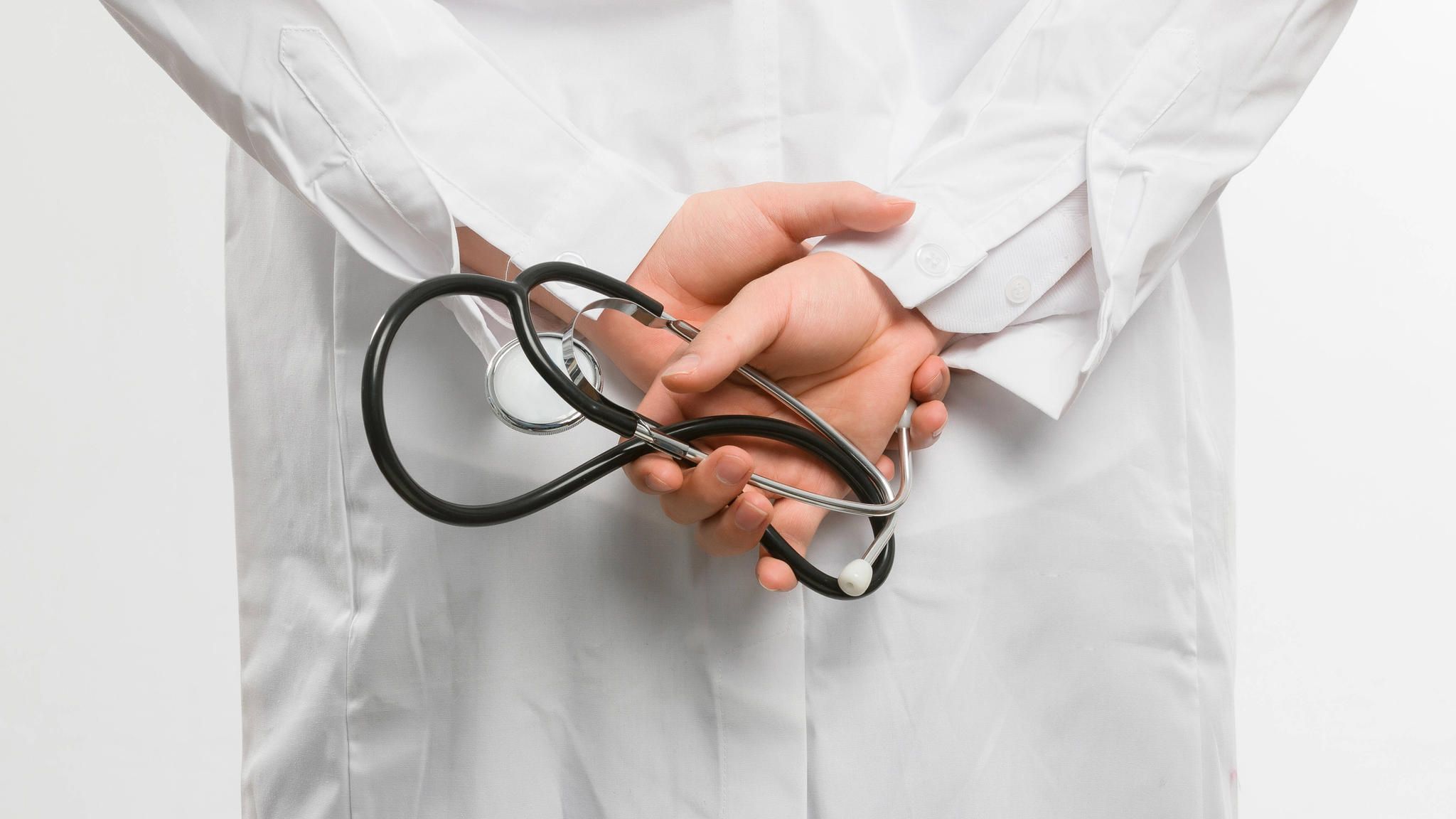Arzt hält Stethoskop hinter seinem Rücken