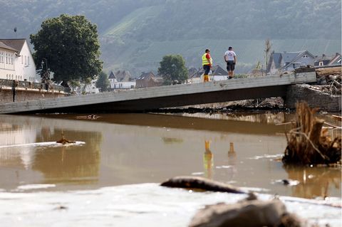Zwei Männer stehen nach dem schwerem Hochwasser im Ahrtal auf einer zerstörten Brücke
