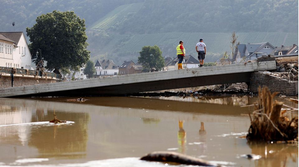 Zwei Männer stehen nach dem schwerem Hochwasser im Ahrtal auf einer zerstörten Brücke