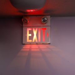 Escape Room Spiel: Ein leuchtendes Exit-Schild hängt an einer Decke.