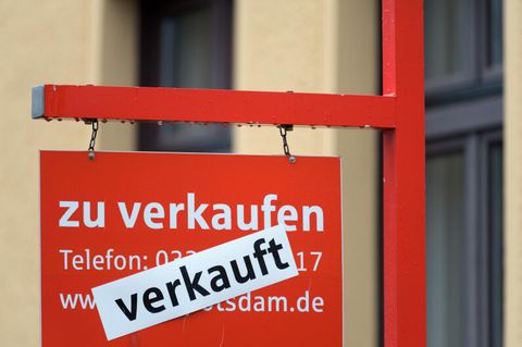 Ein rotes Schild «zu verkaufen» ist mit dem Hinweis «verkauft» überklebt. Dem Immobilienmarkt droht Abwärtsspirale.