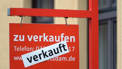 Ein rotes Schild «zu verkaufen» ist mit dem Hinweis «verkauft» überklebt. Dem Immobilienmarkt droht Abwärtsspirale.