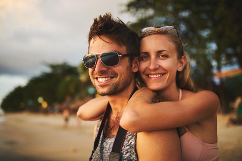 Sonnenbrillen für Männer: Junges Pärchen am Strand, er mit Sonnenbrille