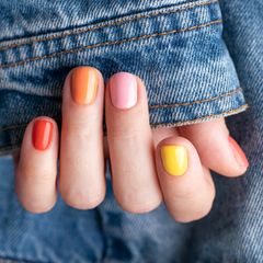 Eine Hand mit bunt lackierten Fingernägeln.