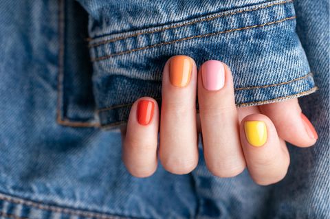 Eine Hand mit bunt lackierten Fingernägeln.