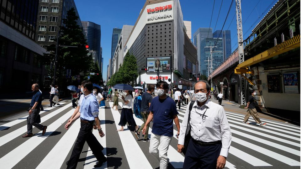 Menschen die über eine Kreuzung in Tokio, Japan, gehen