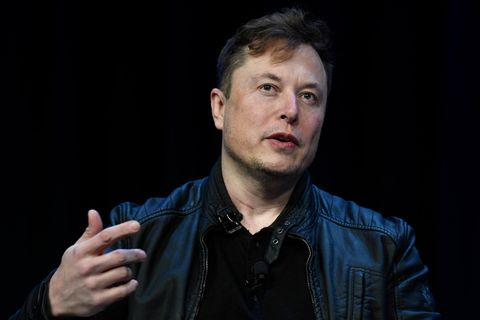 Twitter-Chef Elon Musk gestikuliert, während er auf einer Bühne vor schwarzem Hintergrund spricht