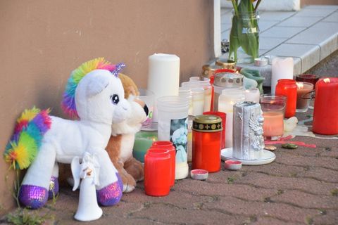 Plüschtiere und Kerzen stehen am Hauseingang zur Wohnung in Hockenheim, in der zwei Brüder tot gefunden worden