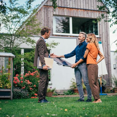 Energetische Sanierung: Ein Paar steht vor ihrem Eigenheim mit einem Energieberater