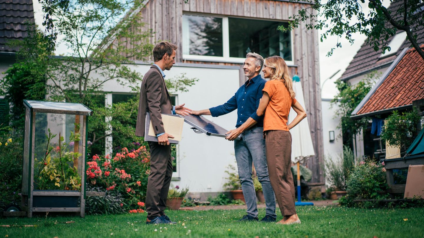 Energetische Sanierung: Ein Paar steht vor ihrem Eigenheim mit einem Energieberater