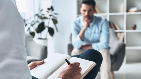 In der Therapie: Ein Mann sitzt auf einem Sessel, eine Frau macht sich Notizen