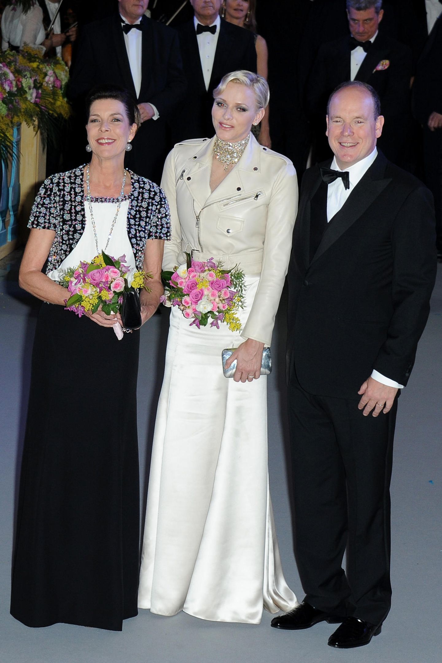 Rock'n'Roll beim Rosenball! Fürstin Charlène strahlte 2013 neben ihrer älteren Schwägerin, Prinzessin Caroline von Hannover, und Ehemann Albert in einer cremefarbenen Lederjacke. Darunter kommt das weiße Kleid von Ralph Lauren hervor. Unter der Jacke versteckt: Das eigens für die Monarchengattin angefertigte Kleid ist an den Schulterpartien mit den gleichen Kristallschnüren besetzt, wie sie Charlène um den Hals trug. Ein gewagter Look – vielleicht mit Bedacht, denn es war der letzte Rosenball der Fürstin. Ab 2014 überlässt sie das Charity-Event Caroline.