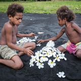 zwei Kinder spielen im dunkelgrauen Sand