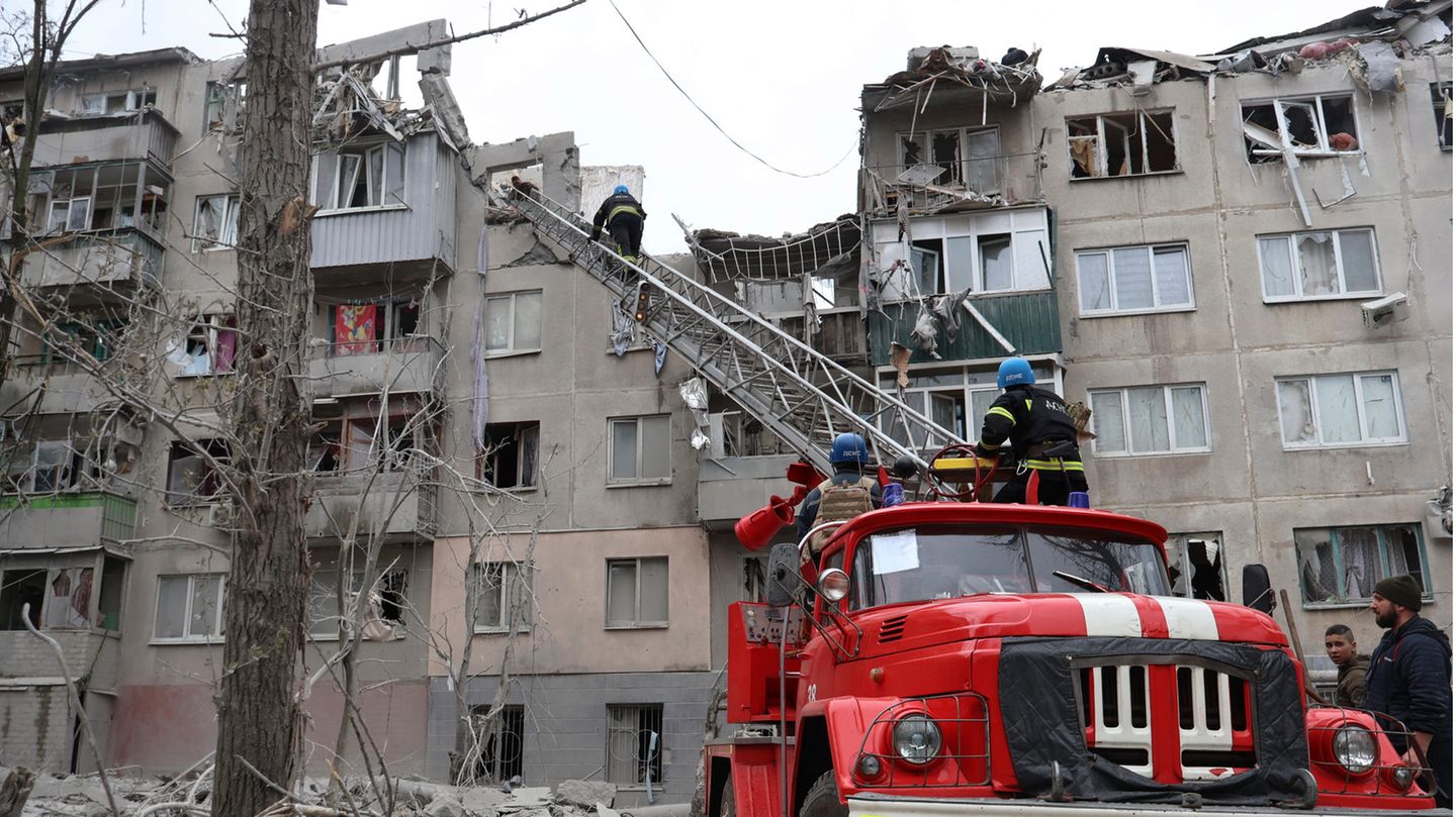 Feuerwehrleute arbeiten daran, ein Feuer zu löschen, während sie nach einem Raketenangriff nach möglichen Opfern suchen