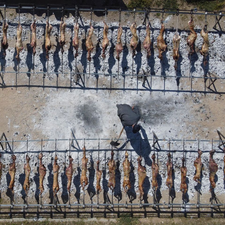 Ein Mann legt Kohle unter die am Spieß gebratenen Lämmer während der orthodoxen Osterfeierlichkeite