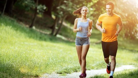 Eine Frau und ein Mann joggen gemeinsam durch einen Park