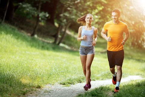 Eine Frau und ein Mann joggen gemeinsam durch einen Park
