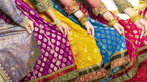 Mehrere Frauen präsentieren ihre Saris. Zu sehen sind Hände, die die bunten Stoffe halten.